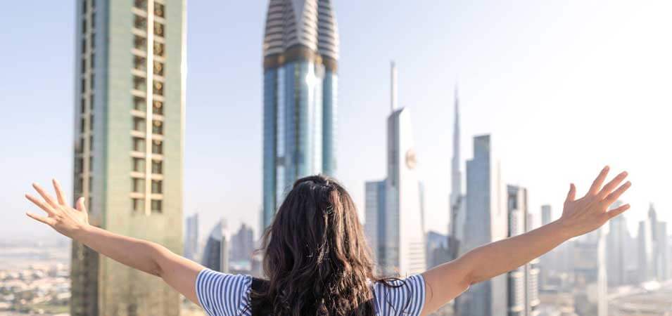 tourist opens her arms in front of some skyscrapers